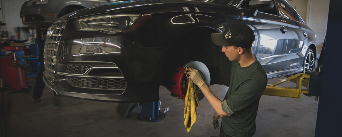 Worker in BWP Car Maintenance Service in Denver, CO cleans disks brakes of the Audi automobile.