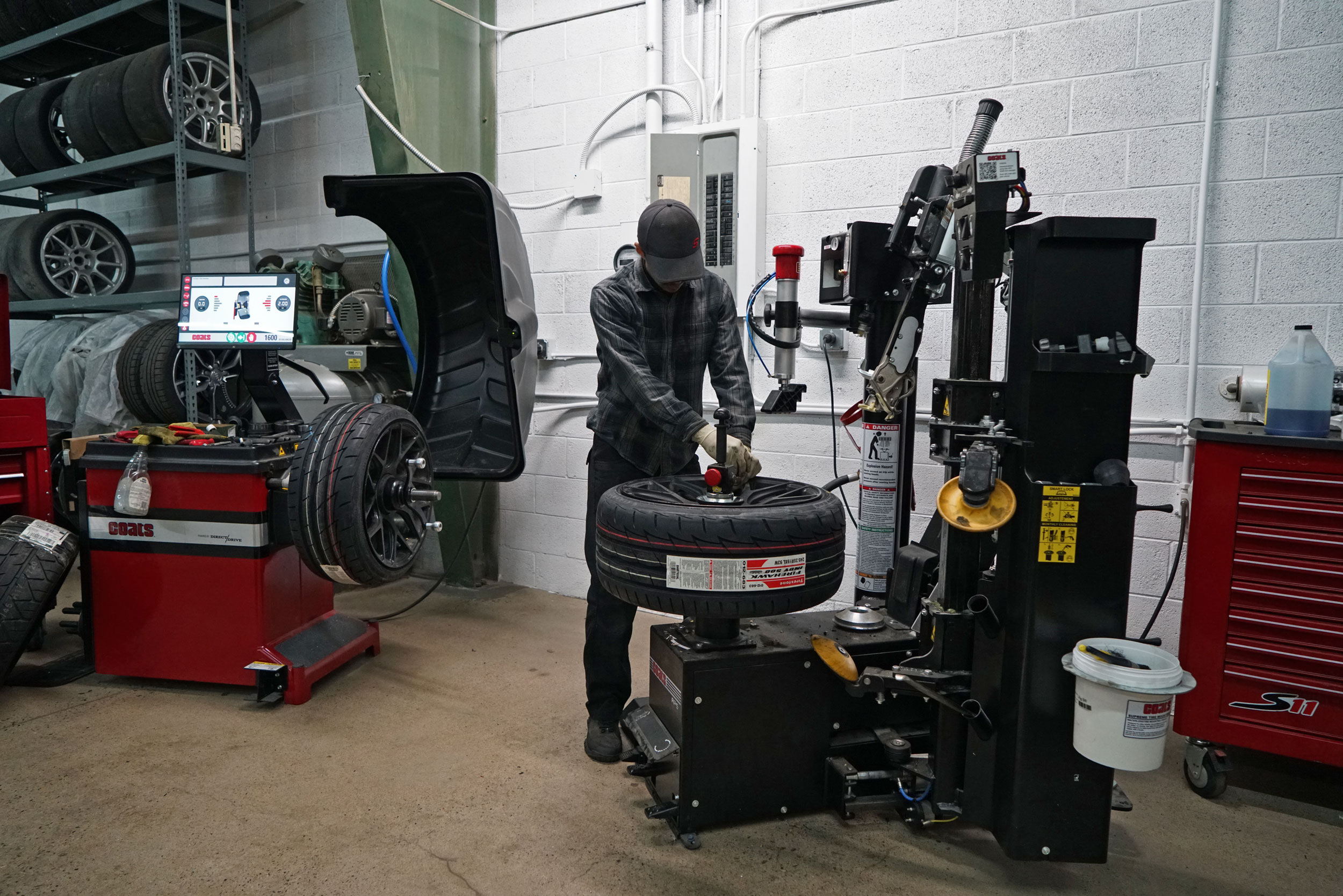 Image of tire alignment being provided in the workshop of Bluewater Performance, a mechanic is repairing the tire.