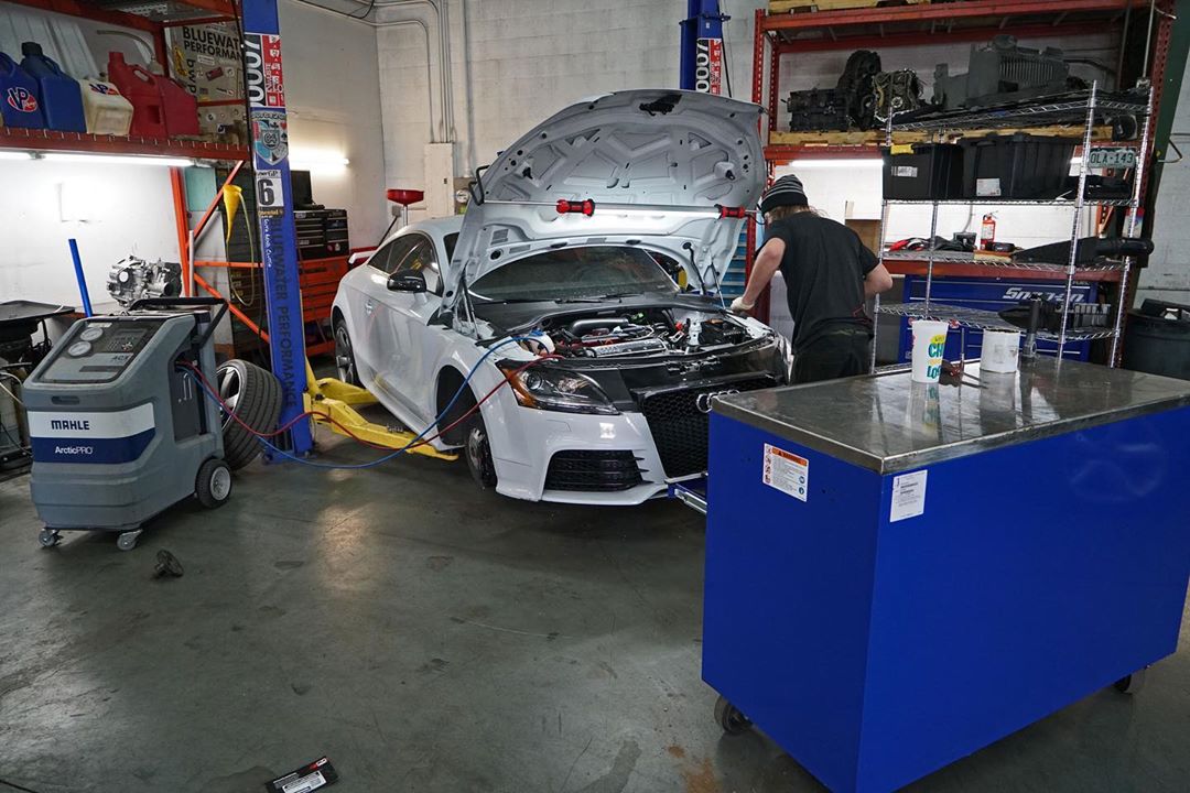 Image of white car receiving an oil change service by a technician