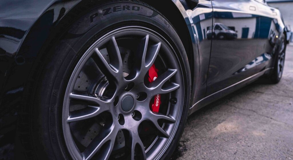 a titanium wheel with red calipers on a black sports car