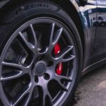 a titanium wheel with red calipers on a black sports car