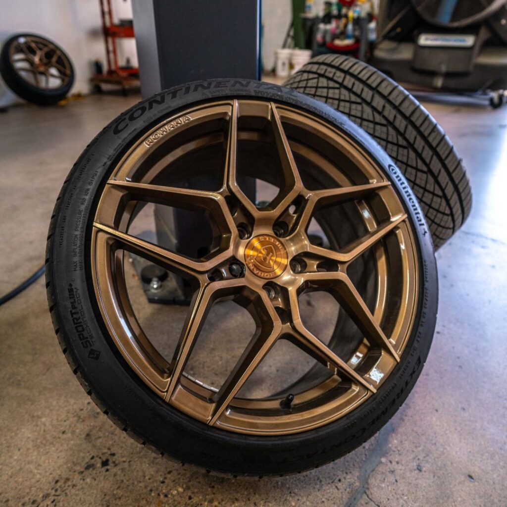 a wheel with a copper finish and thin racing tires leaning against a post