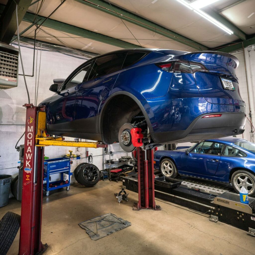 a blue sports car lifted on a hydraulic lift with no wheels and red brake calipers