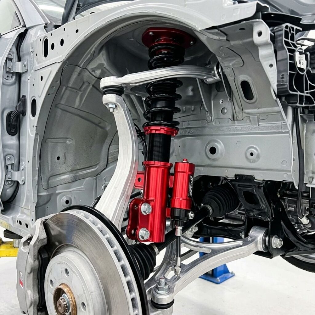 A close-up of a newly installed, premium suspension strut on a clean vehicle chassis in a pristine shop.